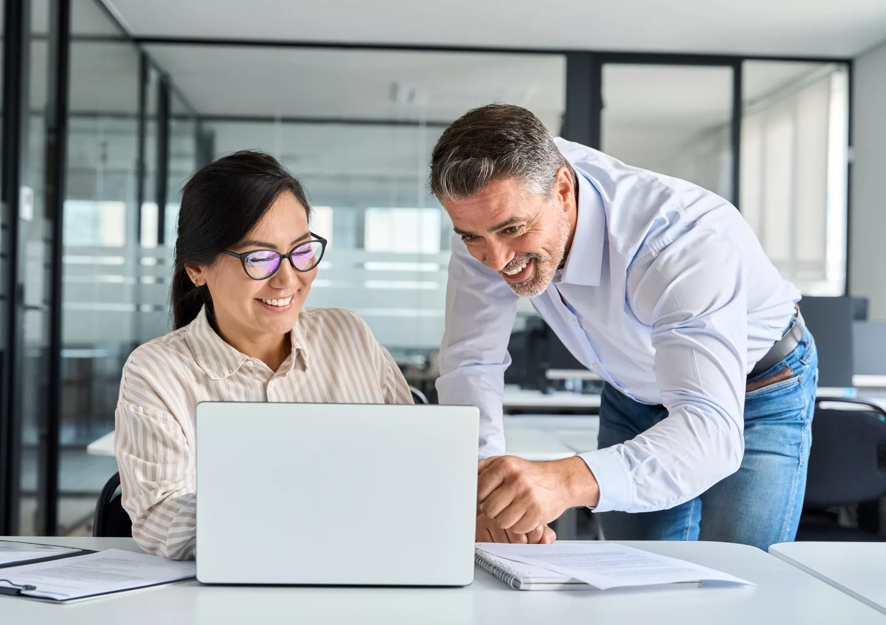 image of two coworkers smiling as they look at a laptop